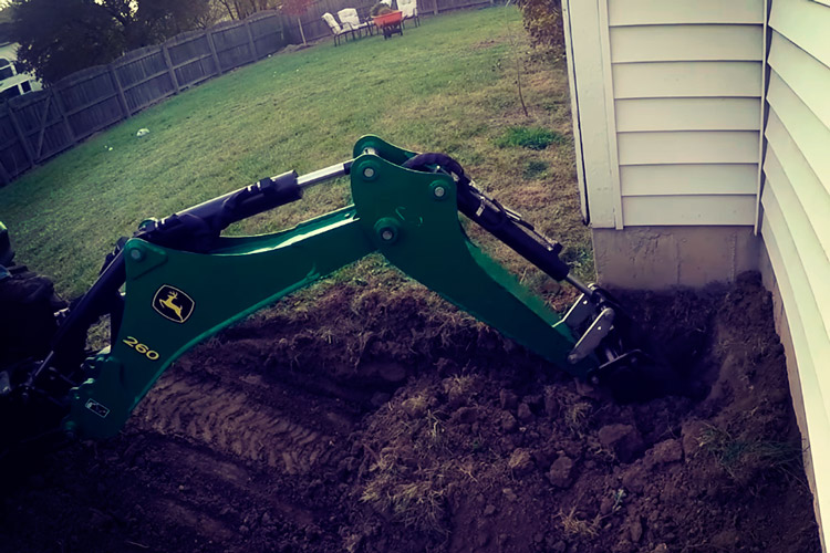 Трактор копает землю для укладки труби ниже уровня промерзания грунта